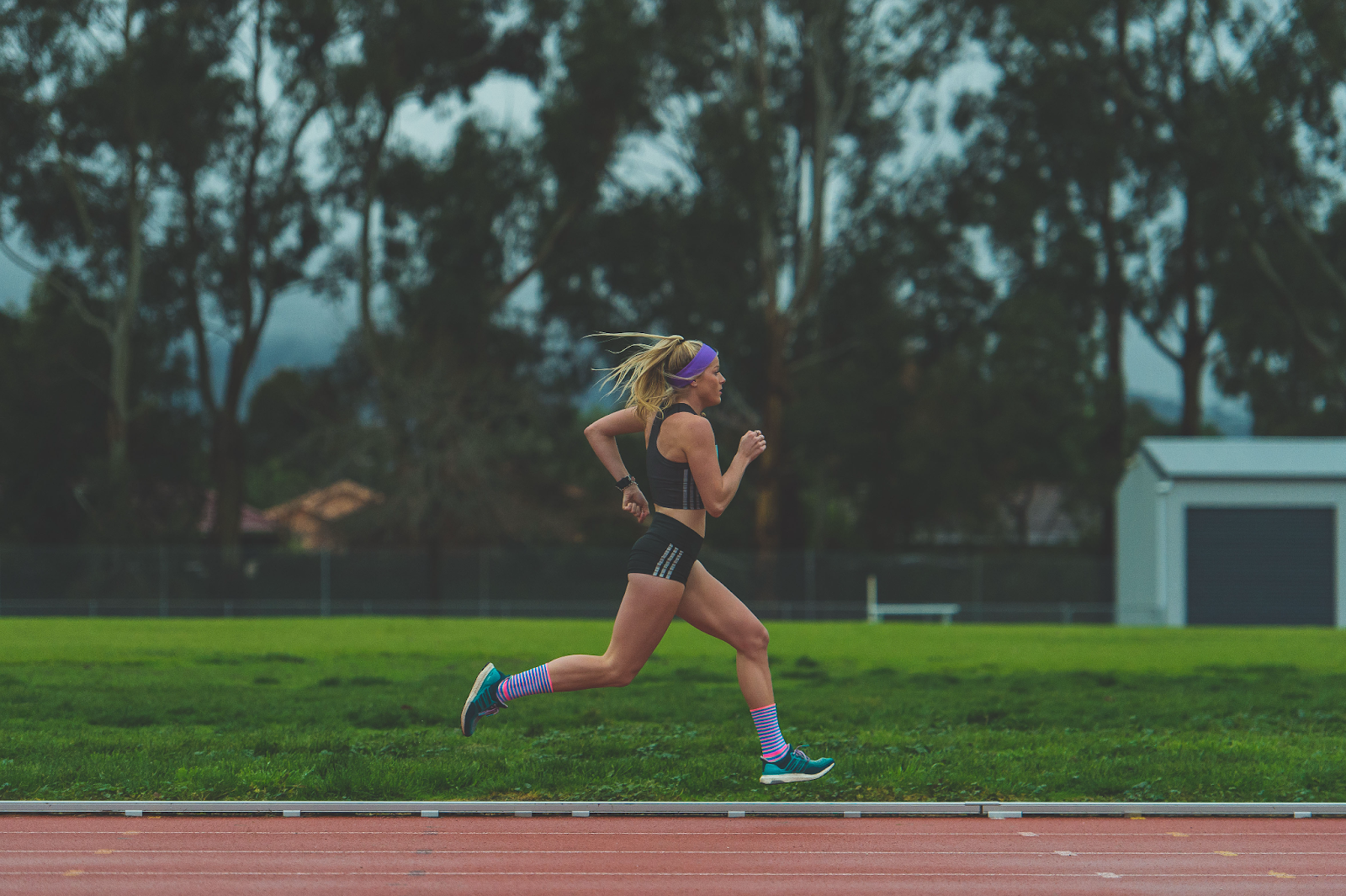 girl running on track with grass in background