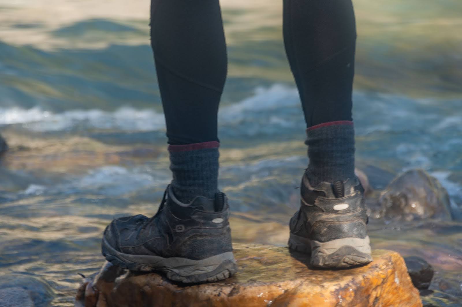 person on a rock by the water wearing calf-length wool socks