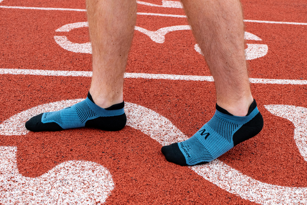 men's legs with black and blue socks on a running track