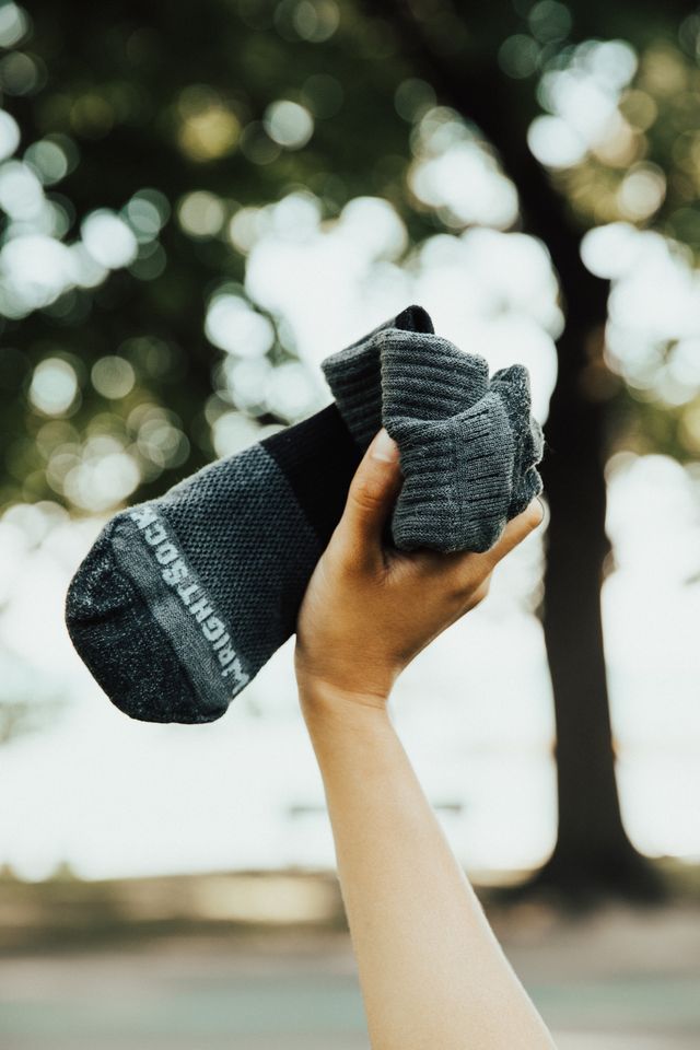 Person holding two black socks with a blurred natural background.