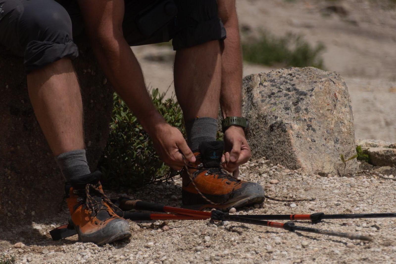 A person tying their shoe on a mountian and wearing Wrightsock Double Layer Hiking Socks.