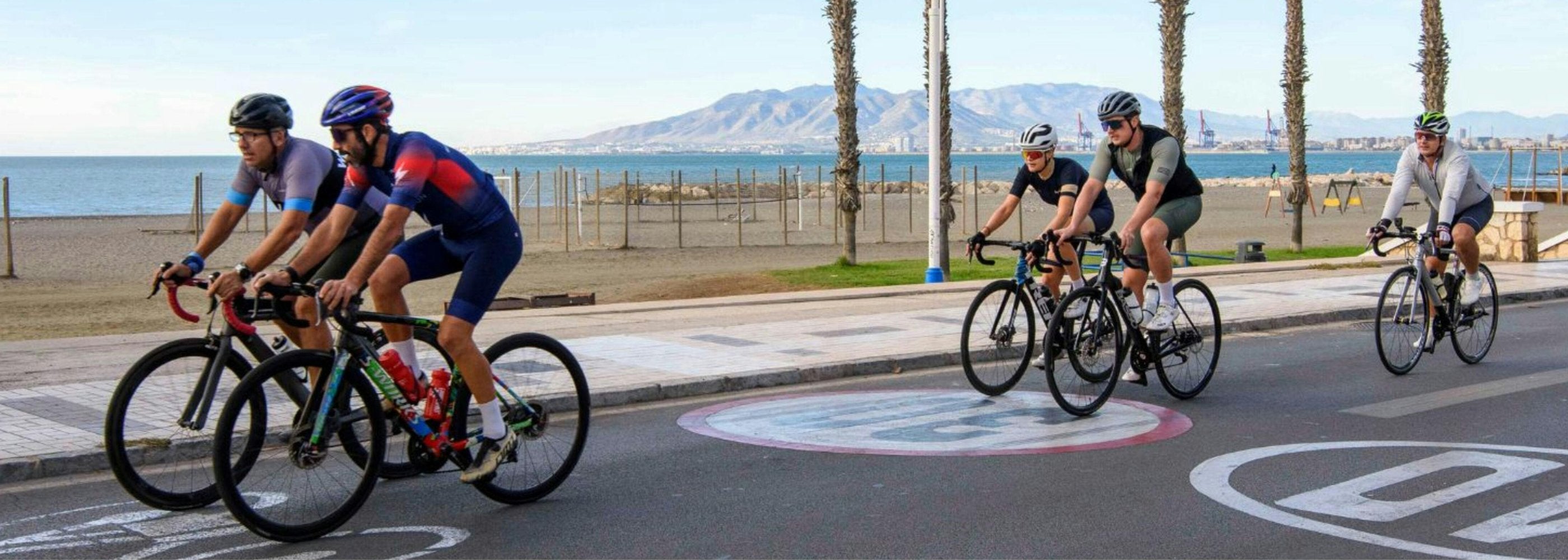 group of cyclists riding down boardwalk with ocean in background