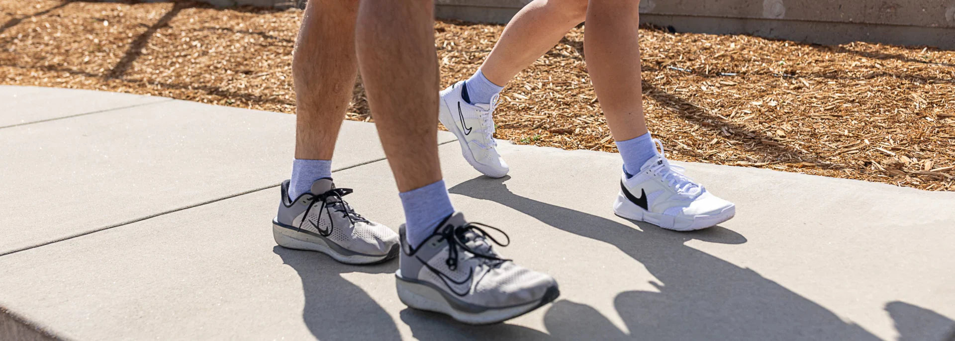 A pair of people walking on a sidwalk and wearing Wrightsock Single Layer Everyday Socks.