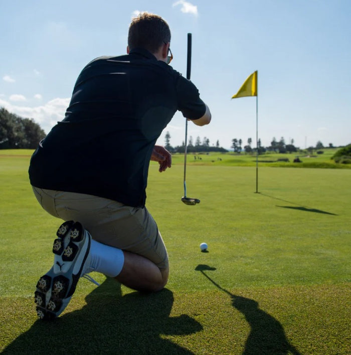 Golfer preparing to putt on a green with a yellow flag in the background