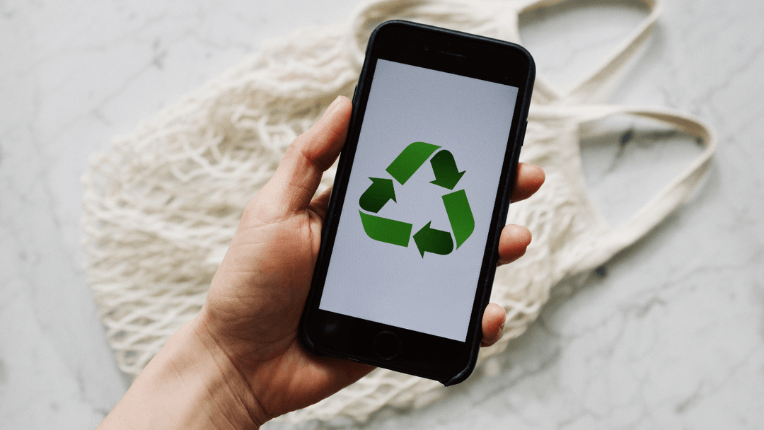 A person holding a phone with a recycling logo on the screen.