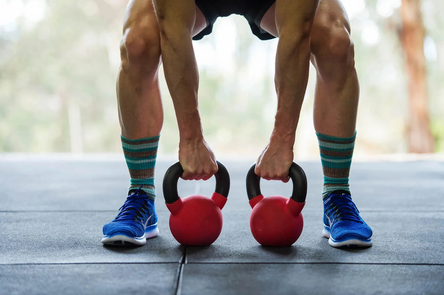 A person in a gym preparing to lift two dumbbells.